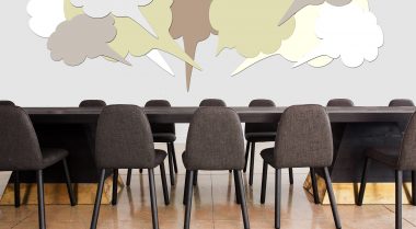 Speech bubbles graphics are positioned above an empty set of tables and chairs