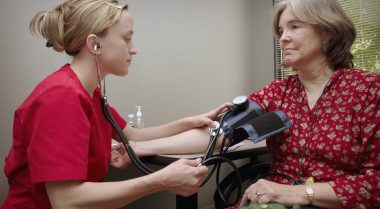 Older woman having her blood pressure taken by a nurse